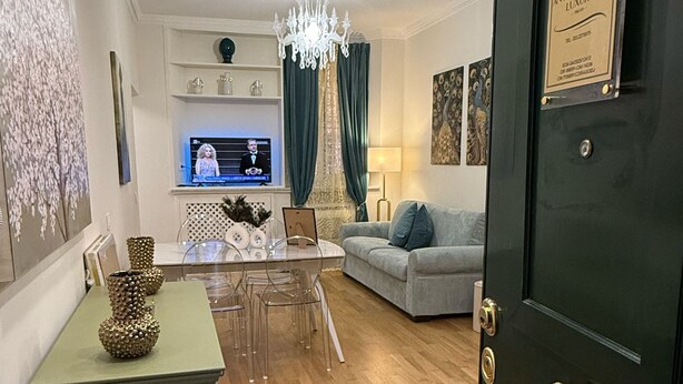 Ein modernes Wohnzimmer mit einer Couch, einem Esstisch mit Stühlen, einer Chandelier und einem Fernseher.