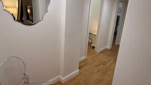 Ein Korridor mit Holzboden, weißen Wänden und einem großen Spiegel.