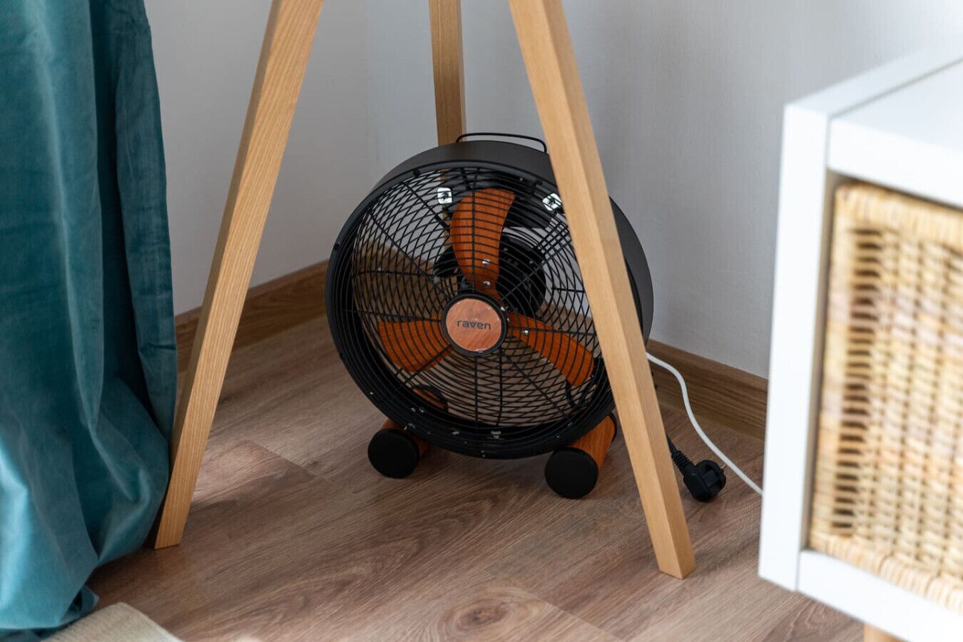 Ein Standventilator mit Holzfuß und eingestecktem Kabel.