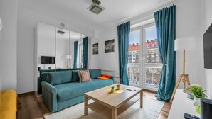 A modern living room with a teal sofa, a wooden coffee table, and a large window with curtains.
