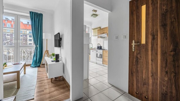 A modern apartment with a living room, kitchen, and balcony.