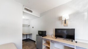 A compact hotel room with a kitchenette, a flat-screen TV, a desk, and a bed. - Extended Stay by Welcome INN (Blue Springs)