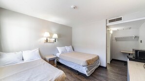 A hotel room with two beds, a desk, a chair, a lamp, a microwave, and a vent. - Extended Stay by Welcome INN (Blue Springs)