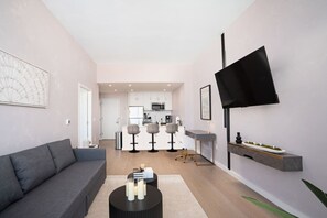 Una sala moderna con un sofá gris, una mesa de centro con velas y un televisor montado en la pared.