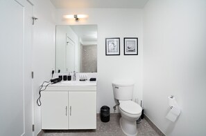 Een moderne badkamer met een wit badkamermeubel, een toilet en twee afbeeldingen in lijsten aan de muur.