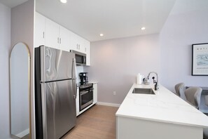 Una cocina moderna con electrodomésticos de acero inoxidable, encimera blanca y diseño minimalista.