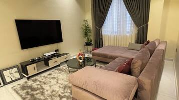 A modern living room with a flat-screen TV, a sofa, a coffee table, and a potted plant.