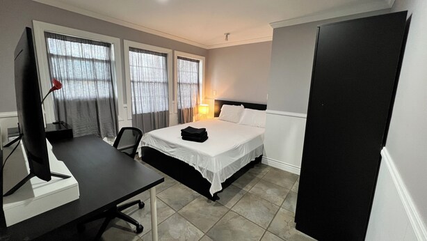 A hotel room with a bed, desk, chair, and a TV.