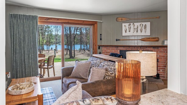 Una sala de estar acogedora con chimenea, comedor y vista al lago.