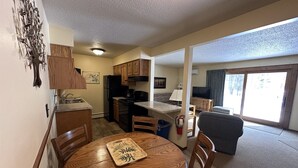 A compact living space with a kitchen, dining area, and a large sliding glass door to a balcony.