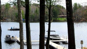 Un muelle a orillas del lago con barcos, un banco y árboles.