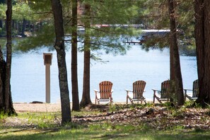 Une vue sur le lac avec trois chaises Adirondack et une mangeoire à oiseaux.