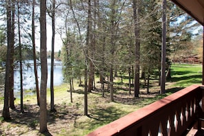 Metsäinen alue, jossa on järvi, puinen terassi ja nurmikenttä.