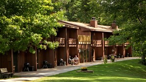 A lodge with a covered patio, outdoor seating, and a well-maintained lawn.