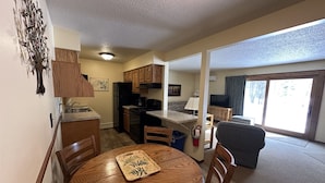 A compact living space with a kitchen, dining area, and a large sliding glass door to a balcony. - Lake Forest Resort – Relax on a Pristine Sandy Beach in the Northwoods! (Eagle River)