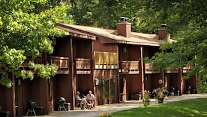 A wooden lodge with outdoor seating, a covered patio, and a well-maintained lawn. - Lake Forest Resort – Relax on a Pristine Sandy Beach in the Northwoods! (Eagle River)