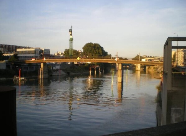 A bridge over a river with buildings and a tower in the background. - Convenient location (Alfortville)