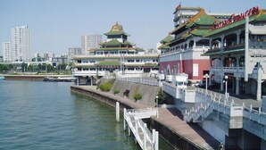 Un hôtel situé au bord de l’eau, doté d’une architecture traditionnelle, d’un quai et offrant une vue sur le paysage urbain en arrière-plan.