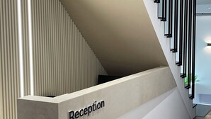 Una recepción de diseño moderno, una escalera con barandillas negras y un suelo de madera.