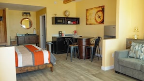 A room with a bed, a desk with a chair, a sofa, a microwave, a globe, and a clock on the wall. - NEW! The Shipwreck Studio (Corpus Christi)