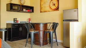 A compact kitchen with a round table, bar stools, a microwave, a coffee maker, a refrigerator, and a globe on a shelf. - NEW! The Shipwreck Studio (Corpus Christi)