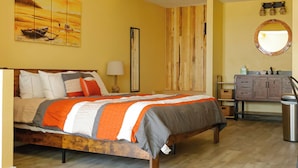A bedroom with a wooden bed, a nightstand, a dresser, and a mirror. - NEW! The Shipwreck Studio (Corpus Christi)
