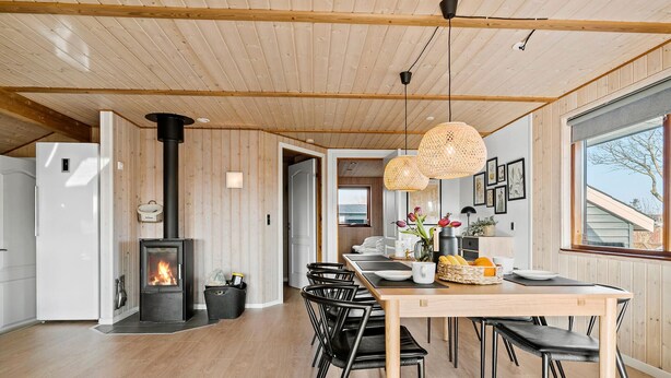 A modern kitchen with a central island, a built-in stove, and a dining area with black chairs and a wooden table.