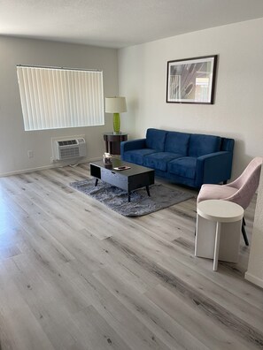 Una sala de estar con un sofá azul, una mesa de centro, una lámpara y una silla.