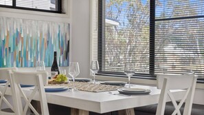 A dining area with a white table set for four, including plates, glasses, and a bottle of wine. - NorthStar 5 (Jindabyne)