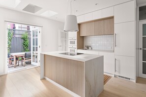 A modern kitchen with a central island, white cabinetry, and a view to an outdoor patio. - Hampton Beach Pearl Near Beach (Hampton)