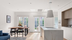 Een moderne keuken met een marmeren eiland, houten kasten en een eethoek met een tafel en stoelen.