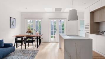 A modern kitchen with a marble island, wooden cabinets, and a dining area with a table and chairs.