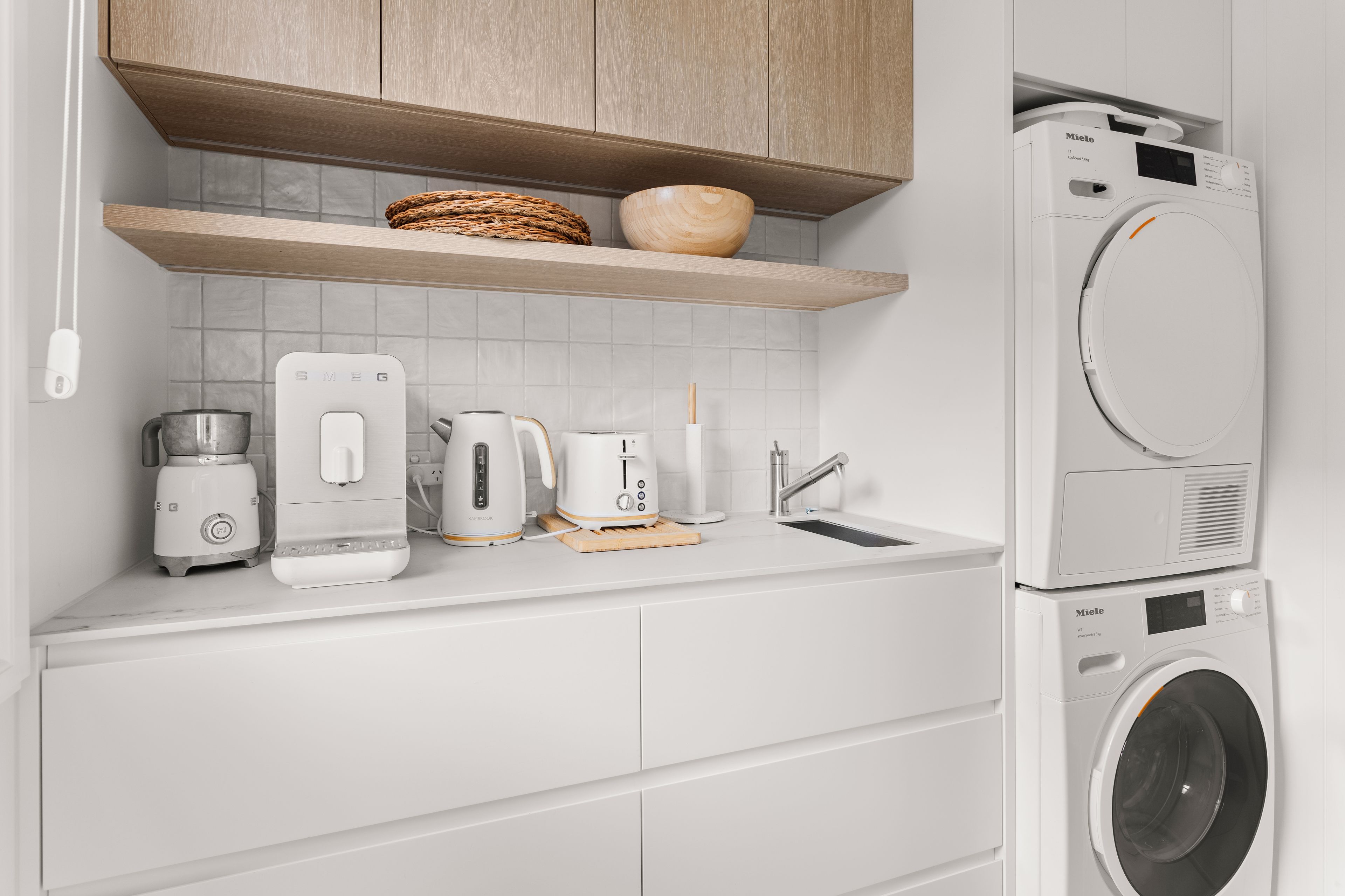 A modern kitchen with a built-in washing machine, a coffee maker, a toaster, and a kettle.