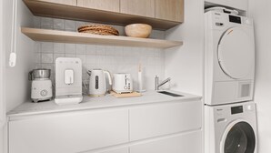 Een moderne keuken met een inbouw wasmachine, een koffiezetapparaat, een broodrooster en een waterkoker.