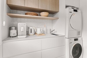 A modern kitchen with a built-in washing machine, a coffee maker, a toaster, and a kettle. - Hampton Beach Pearl Near Beach (Hampton)