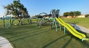 A playground with a yellow slide and various climbing structures.