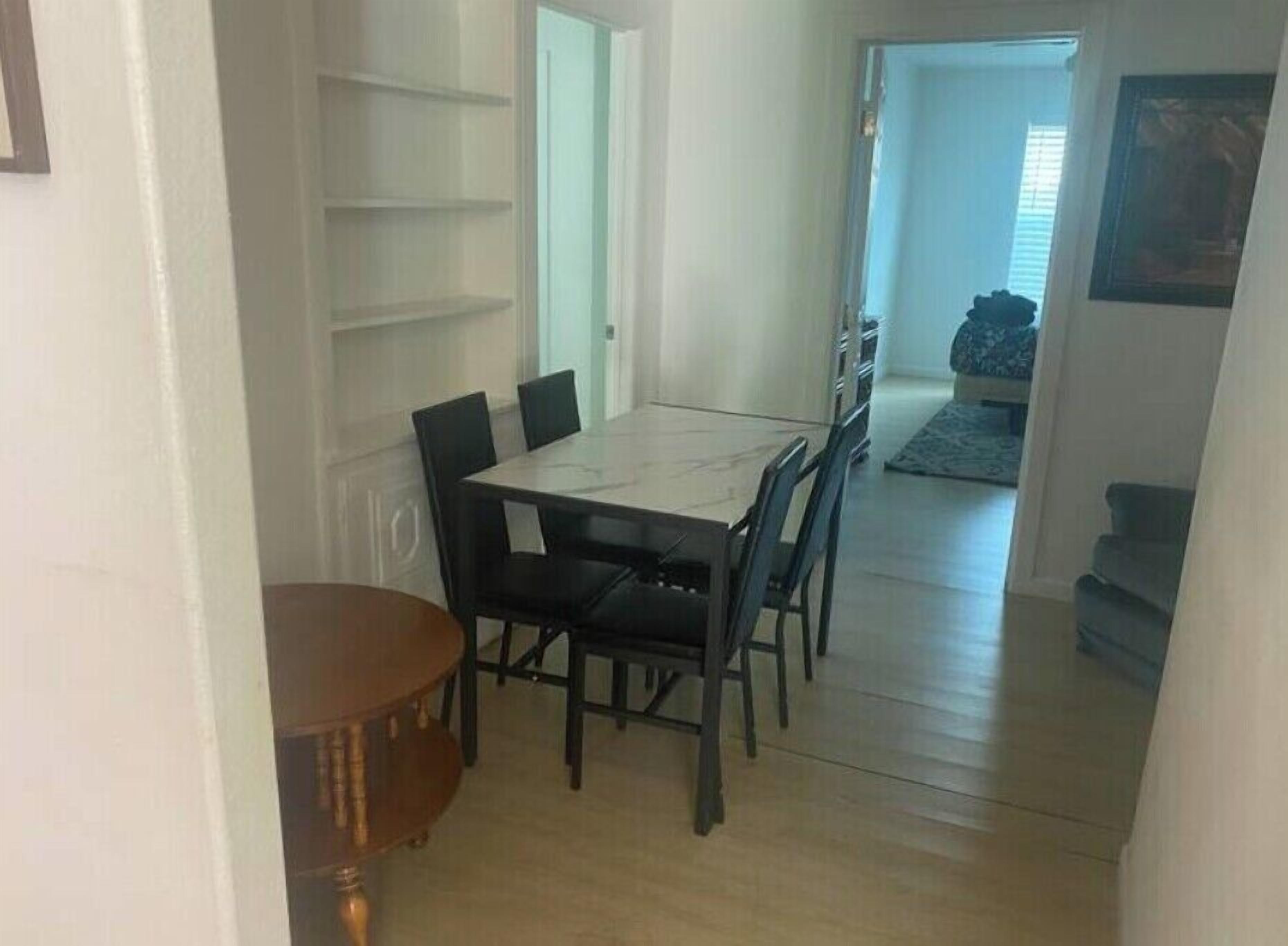 En matplats med ett bord och stolar, ett litet runt bord och en dörr som leder till ett annat rum.