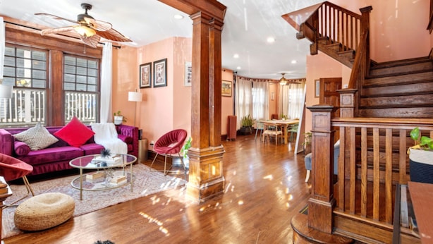 Un salon spacieux avec un escalier en bois, un canapé rouge et un ventilateur de plafond.
