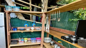 A rustic kitchen with wooden shelves holding various kitchen utensils, containers, and cookware. - Private cabin with stunning views & home-cooked meals (Provincia de Puntarenas)