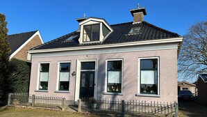 A two-story house with a dark tiled roof, a small dormer window, and a brick chimney. - Independent apartment in Jorwert near Leeuwarden, Sneek, Bolsward and Franeker (Jorwert)