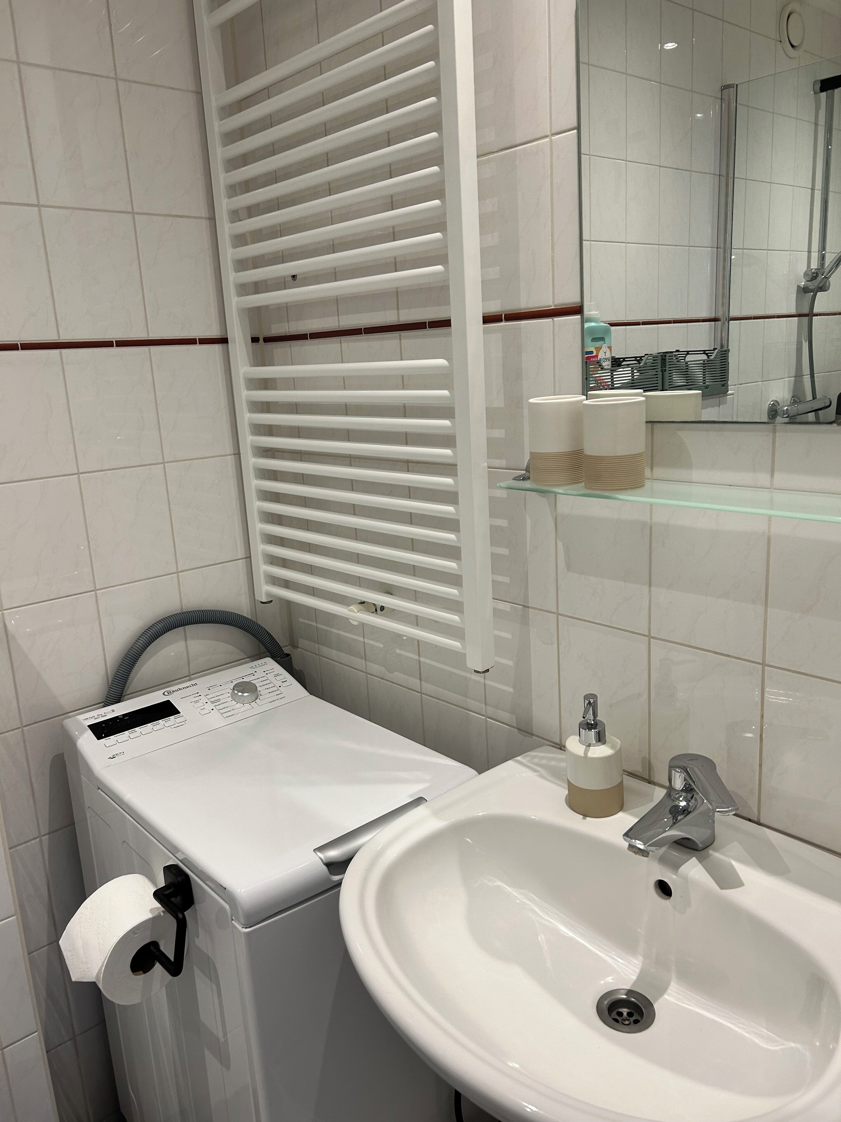 Une salle de bain équipée de toilettes, d’un lavabo, d’un miroir et d’un porte-serviettes.