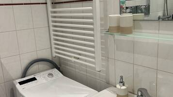 A bathroom with a toilet, a sink, a mirror, and a towel rack.