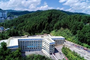 A large building with a flat roof, surrounded by dense forest and a highway. - Senlin Hotel (Guiyang)