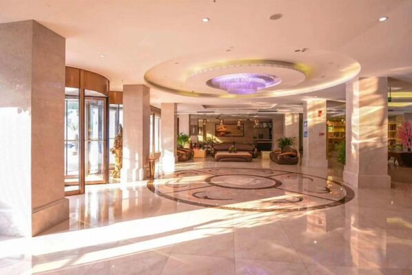 A spacious lobby with a circular floor design, a reception area, and a seating area with sofas.