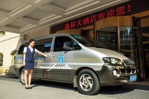 A silver van parked in front of a building with a sign in a foreign language. - Senlin Hotel (Guiyang)