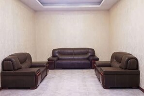 A room with a brown leather sofa set and matching armchairs, a tiled floor, and a plain wall. - Senlin Hotel (Guiyang)