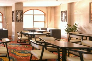 A hotel dining area with tables and chairs, large windows, and decorative wall panels. - Senlin Hotel (Guiyang)