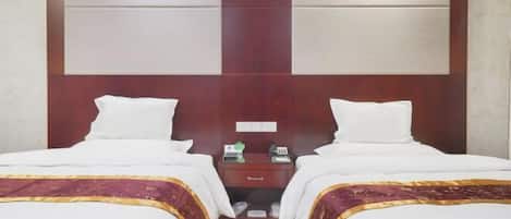 A hotel room with two beds, a wooden headboard, a nightstand, and a small drawer.