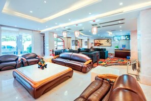 A hotel lobby with leather sofas, a coffee table, and a television.