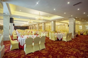 A banquet hall with round tables and chairs, a red carpet, and a chandelier. - Senlin Hotel (Guiyang)